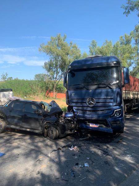 Caminhão azul da Mercedes envolvido em um acidente com um carro preto colidido frontalmente na estrada.