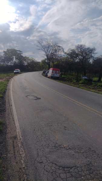 Estrada em curva com vegetação ao redor e uma van parada na beira da pista.