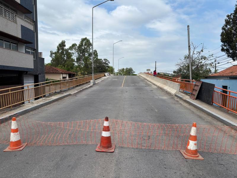 Ponte com interdição para veículos, cercada por cones laranja e fita de segurança, em um dia nublado.