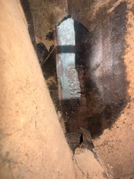Vista detalhada de uma superfície com uma marcação visível em metal e áreas de desgaste, embrenhada em uma estrutura de material mais claro.