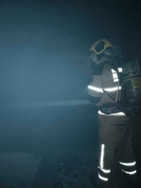 Bombeiro usando equipamento de proteção em ambiente com fumaça.