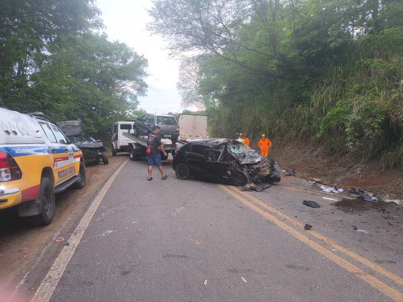 Acidente de carro em estrada com veículo destruído e equipes de resgate no local.