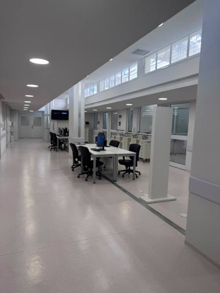 Vista de um espaço de escritório moderno com mesas, cadeiras e iluminação iluminada.