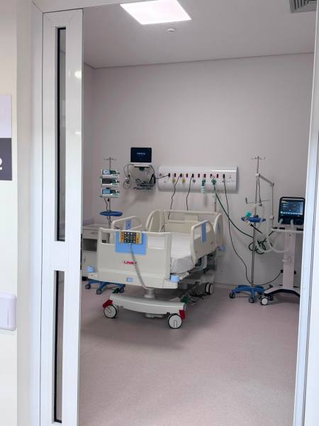 Quarto de hospital com cama hospitalar, equipamentos médicos e monitores.