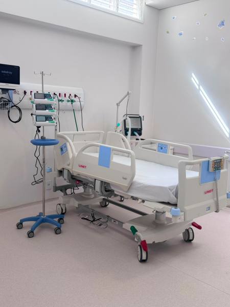 Quarto de hospital com uma cama hospitalar equipada e um suporte para soro.