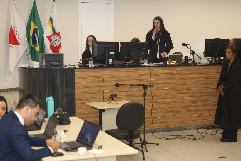 Audiência judicial com advogados, juízes e equipamentos de informática em um ambiente de tribunal.