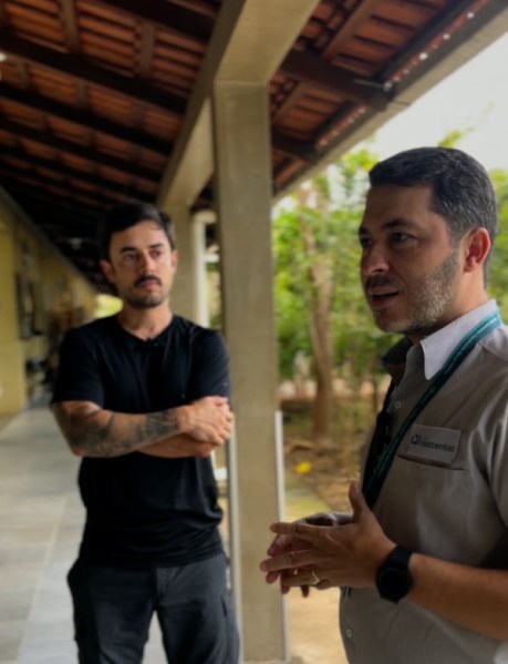 Dois homens conversando em um ambiente ao ar livre, um deles gesticulando enquanto fala.