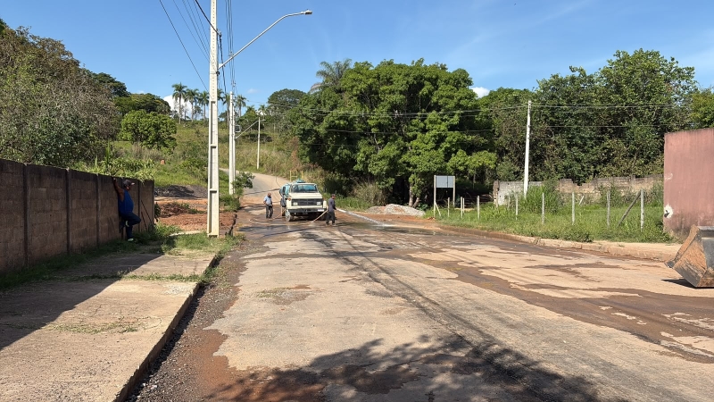 Caminho asfaltado em reparo com dois homens trabalhando e uma caminhonete estacionada ao lado.