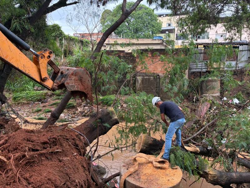 Homem trabalhando em uma área de desmatamento, utilizando uma máquina para remover árvores ao lado de um rio.