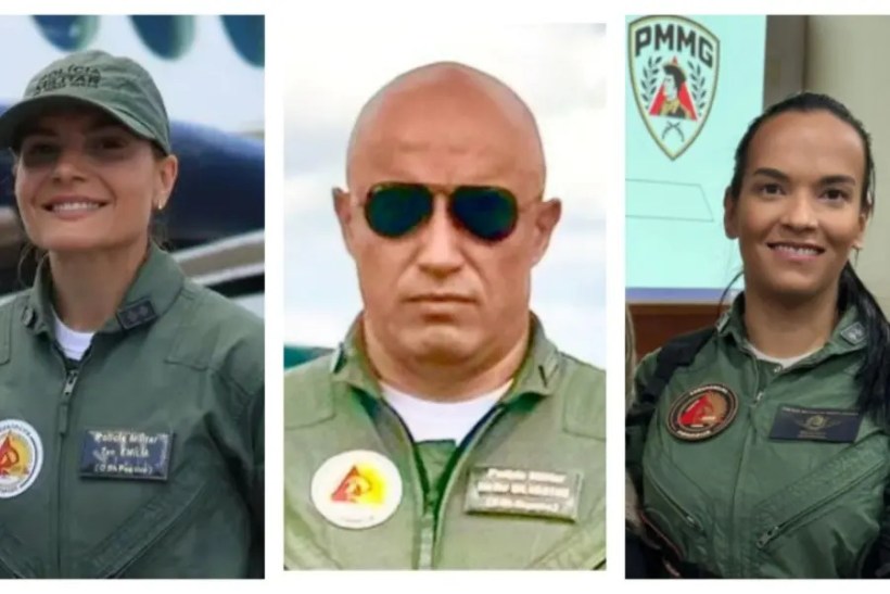 Três militares em trajes de voo; mulher sorridente à esquerda, homem sério no centro e mulher sorridente à direita, todos com distintivos no uniforme.