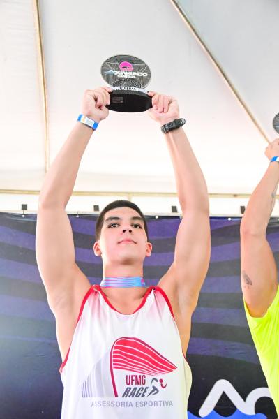 Jovem atleta segurando um troféu acima da cabeça em uma cerimônia de premiação.