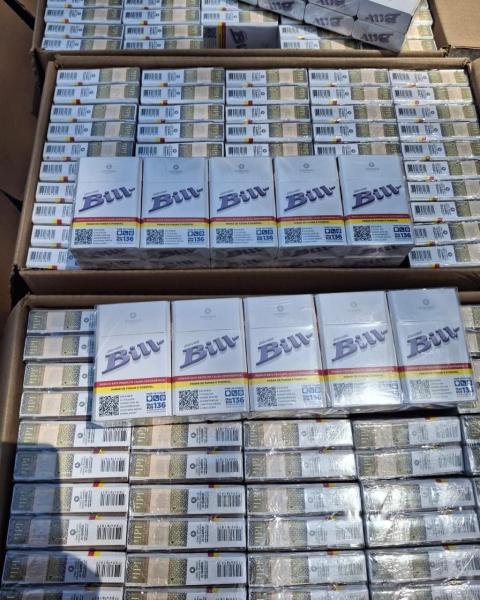 Caixas de cigarros da marca 'Bill' empilhadas em uma superfície, visíveis em um ambiente claro.
