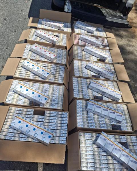 Caixas de cigarros empilhadas em uma superfície ao ar livre, com embalagens visíveis em diferentes cores e marcas.