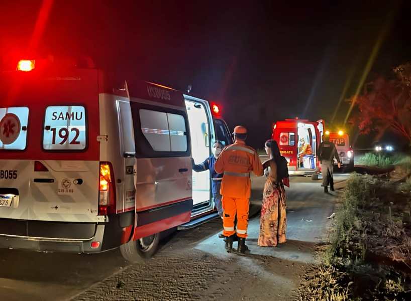 Atendimento de emergência noturno com ambulâncias do SAMU e profissionais de saúde em uma estrada.