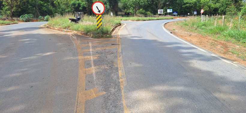 Interseção de estrada com placa de sinalização e vegetação ao redor.