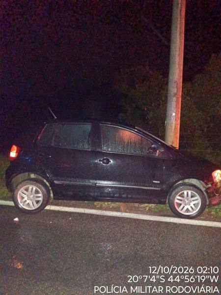 Carro preto estacionado em uma estrada à noite, com gotas de chuva na lataria.