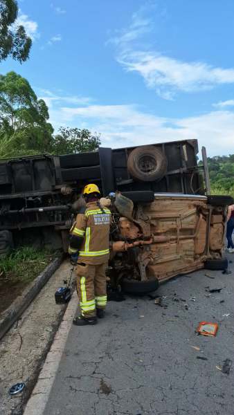 Veículo de grande porte capotado na estrada, com bombeiros realizando o resgate.