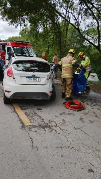 Cenas de um acidente de carro, com um veículo branco estacionado na estrada e bombeiros trabalhando na cena.
