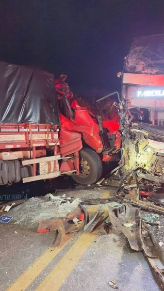 Acidente entre dois caminhões à noite, com um veículo parcialmente destruído e danos visíveis na estrutura de ambos.