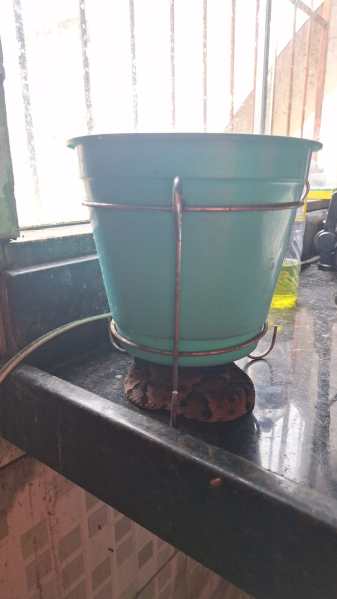 Um balde de plástico azul em uma prateleira, fixado com um suporte de metal e um suporte redondo na parte inferior.
