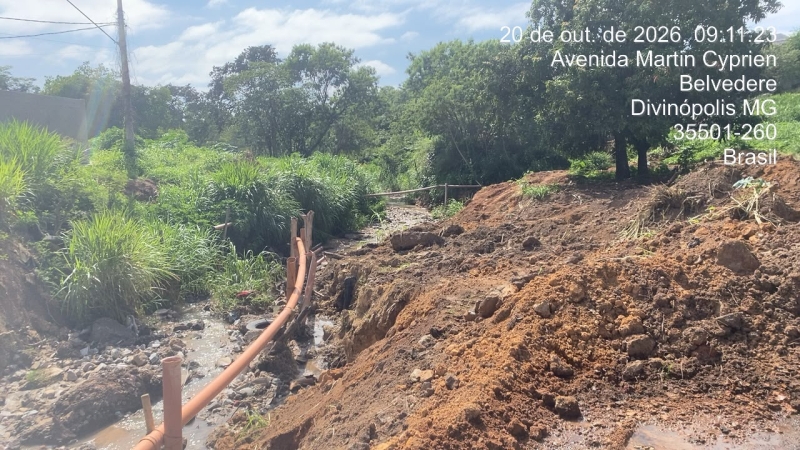 Vista de uma área com terra removida, tubos expostos e vegetação ao fundo, mostrando trabalho de construção ou manutenção em curso.